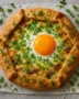 Rustic savory galette with herbs and melted cheese on a wooden serving board