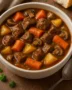 A bowl of classic beef stew with potatoes, carrots, and fresh herbs