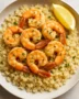 Plated garlic butter shrimp served over seasoned cauliflower rice with herbs and lemon slices